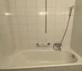 tiled walls, white bathtub, grab bars, shower