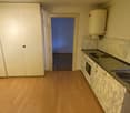 small room with a sink, cabinet, wardrobe, an oven, wooden floor, white wall