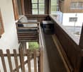 Balcony with wooden sofa, wooden balcony railing, wooden stairs, wooden fence, table on the balcony, view of a street and a building