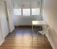 Empty room, wooden floor, white walls, desk, chairs, radiator, windows