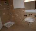 Bathroom with tiled walls, shower, sink, and mirror