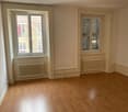 Wooden floor, white walls, two windows, and two radiators. Empty room.