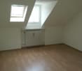 Spacious bedroom with hardwood flooring, white walls, and a skylight window. The room features a radiator heating unit.