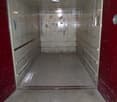 The image shows the interior of an elevator. The walls are tiled, and the floor is concrete. The elevator appears to be in a commercial or industrial building.