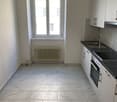 Empty kitchen, white tiles, white cabinets, black countertops, white sink, oven, window with white frame, radiator