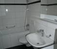 White tiled bathroom with a shower, sink, and toilet.