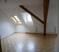 Spacious attic or loft space with wooden beams, skylights, and hardwood flooring. The room appears to be empty and ready for renovation or conversion into a living space.