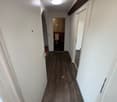 Hallway, hardwood floor, white walls, white doors, bathroom entrance, ceiling light, empty corridor