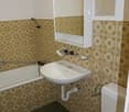 White toilet, white sink, white bathtub, tiled walls, shower head