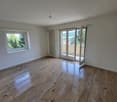 Empty room, wooden floors, sliding doors to balcony, windows, radiator