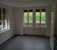 empty room, white walls, dark tiles, three windows, radiator