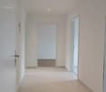 White tiled flooring, white walls, ceiling lights, doorways leading to other rooms, power outlet