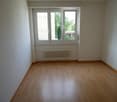 empty room with wooden floor, white walls, window with view to the outside, heating radiator