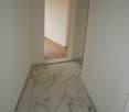 corridor, white marble flooring, white walls, open doorway leading to another room