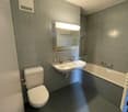 Bathroom with tile flooring, double sink, bathtub, toilet, and mirror.