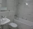 Bathroom: marble tiled, white fixtures, toilet, sink, shower