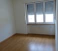 Empty room, hardwood floors, white walls, large window, heater under window