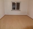 empty room with wooden floor, single window, plain white walls, open door