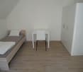 A single bed, a desk with a chair, and a cabinet.