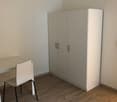 Empty room with a desk, chair, and a closet. Wooden floor and white walls.