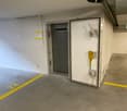 underground parking space, yellow line markings, grey walls, power outlet