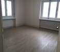 Empty room, white walls, wooden floors, 2 windows, radiators