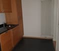 kitchen with wooden cabinets, black countertop, stainless steel sink, and a white radiator