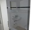 small compact bathroom, white tiles, white sink, mirror, shower cubicle, toilet