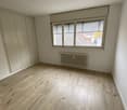 empty room, wooden floors, white walls, large window with blinds, built-in radiator