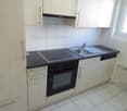 white kitchen cabinets, black countertops, gas stove, oven, sink, dishwasher, natural light from window