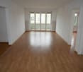 Empty room, wooden floor, sliding glass doors leading to balcony, white walls and ceiling