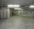underground parking space, concrete floor, metal fence, illuminated by overhead lights