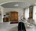 Dining room with wooden furniture, white walls, tiled floor, large window with curtains, table with tablecloth, chairs, cabinet, mirror, and various decorative items