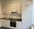 modern kitchen with white cabinets, black countertops, integrated oven and dishwasher, under cabinet lighting