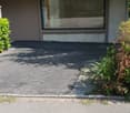 Building with balcony, glass window, red awning, concrete floor, plants