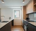 Modern kitchen with wooden floors, white countertops, large sink, and ample cabinet space.