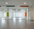 Large empty office space, tile flooring, white walls, glass walls, central pillars