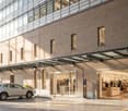 modern building, glass windows, brick wall, car parked in front, awnings, potted plants