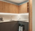 Modern kitchen with wooden cabinets, white countertops, stainless steel sink, and built-in appliances.