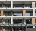 Multi-story modern building with a glass and concrete facade, featuring balconies on each floor and a prominent entrance with the name 'Zurich' displayed.