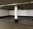 Empty underground parking space with parking spots numbered 17, 18, and 19, and a central white column.