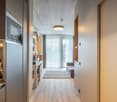 Open-concept living space with kitchen, dining area, and living room. Hardwood floors, concrete ceiling, large windows providing natural light, and a balcony or terrace visible.