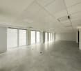Empty room, white walls, gray tiles on the floor, square windows with blinds, white ceiling.