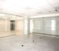 Empty office with glass walls, white ceiling, gray floor, multiple windows
