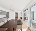 Dining room with a large wooden table, modern chandelier, and large windows