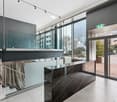 Modern foyer with marble countertop, glass wall, large windows, open staircase, white tiled floor