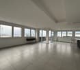 Empty living room with tiled floor, glass doors, windows and a view of the city