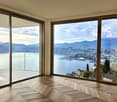 expansive living area with floor-to-ceiling windows leading to balcony, wooden herringbone flooring, stunning lake and city views