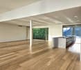 large empty room, hardwood floors, large windows, high ceilings, central kitchen island