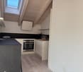 kitchen with oven, kitchen cabinets, island with countertop, wooden floor, skylight